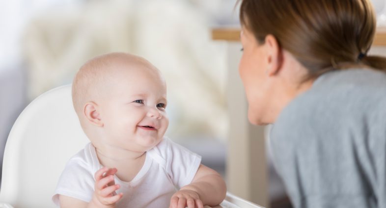 baby in high chair smiling at mom
