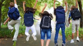 kids wearing backpacks jumping in air