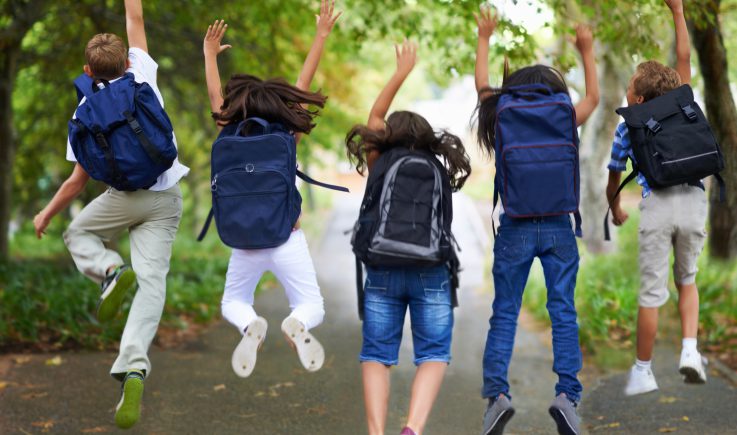 kids wearing backpacks jumping in air