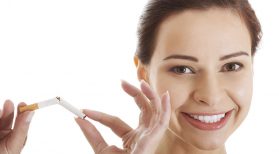 smiling woman breaking cigarette in half