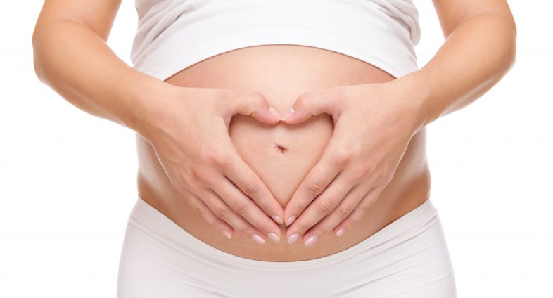 pregnant woman holding belly with hands in shape of a heart