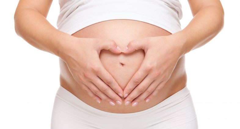 healthy pregnancy - pregnant woman holding belly with hands in shape of a heart