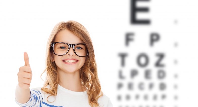 young girl wearing glasses with eye chart in background