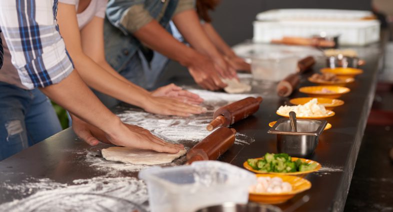 Hands of people making pizzas together