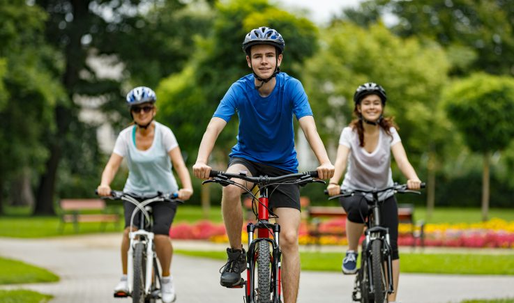 two teens and mom on bikes in park