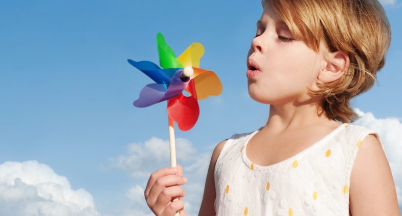 girl blowing pinwheel outdoors