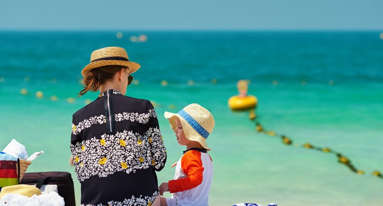 mom and toddler boy on beach wearing sun hats