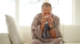senior man with flu blowing nose