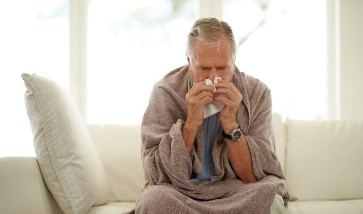 senior man with flu blowing nose