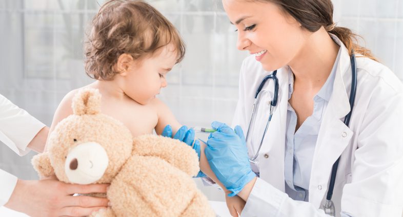 young girl with teddy bear being vaccinated