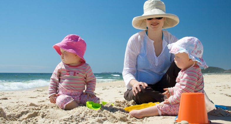 Mom and babies at beach in sun hats