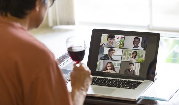 Individual drinking wine during video call