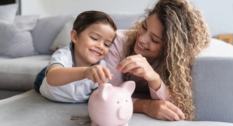 Mother and son putting coin into piggy bank