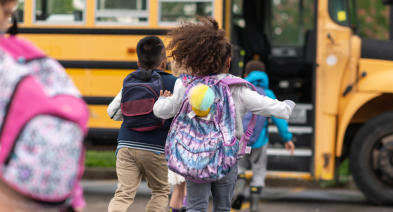 Young kids running to get on a school bus