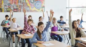 Students with arms raised in classroom