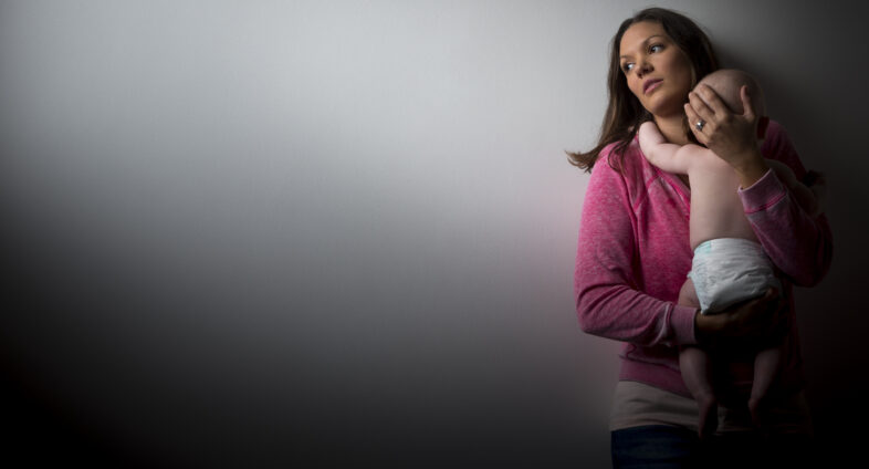 New mom sitting by crib looking upset